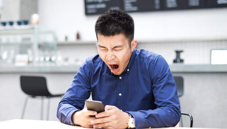 Man looking at cell phone and yawning